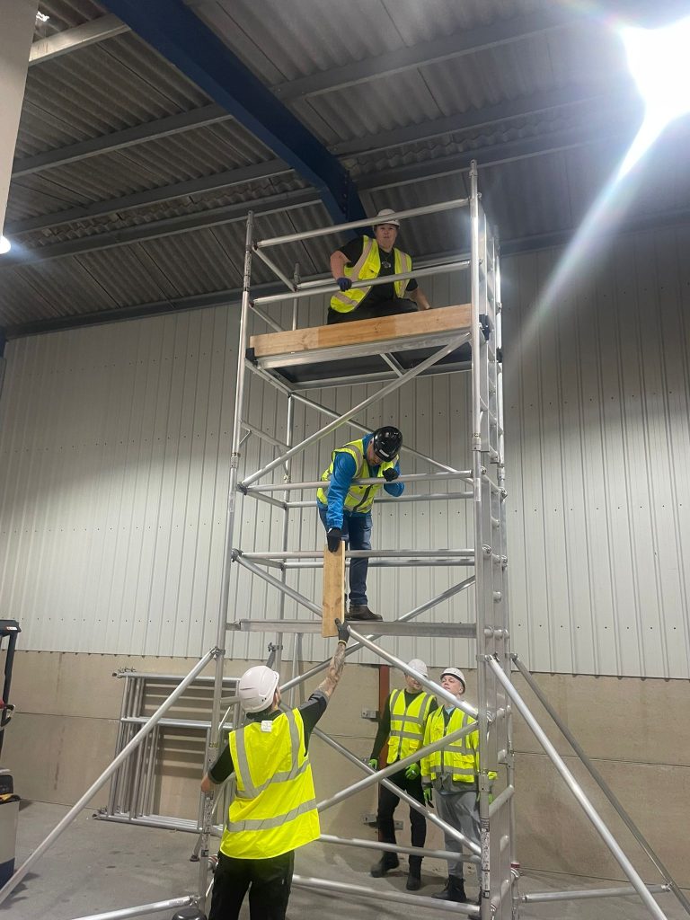 Construction workers assembling indoor scaffolding tower.