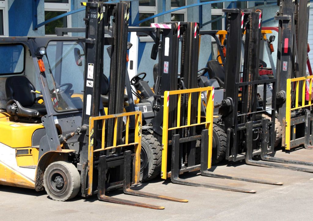 Row of parked forklifts outside building