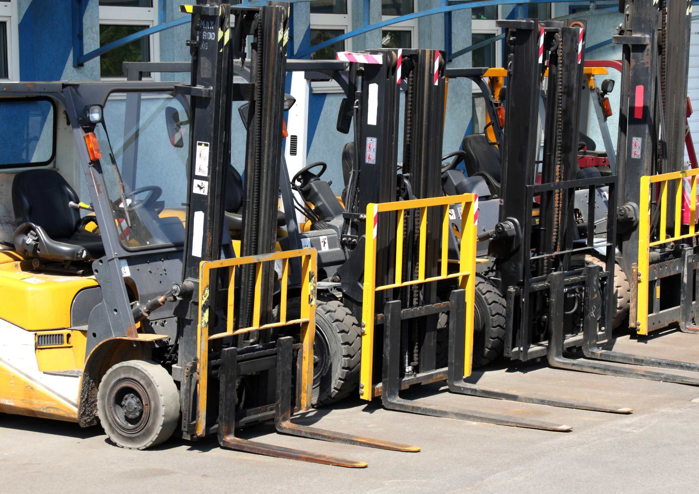 Row of parked forklifts outside building