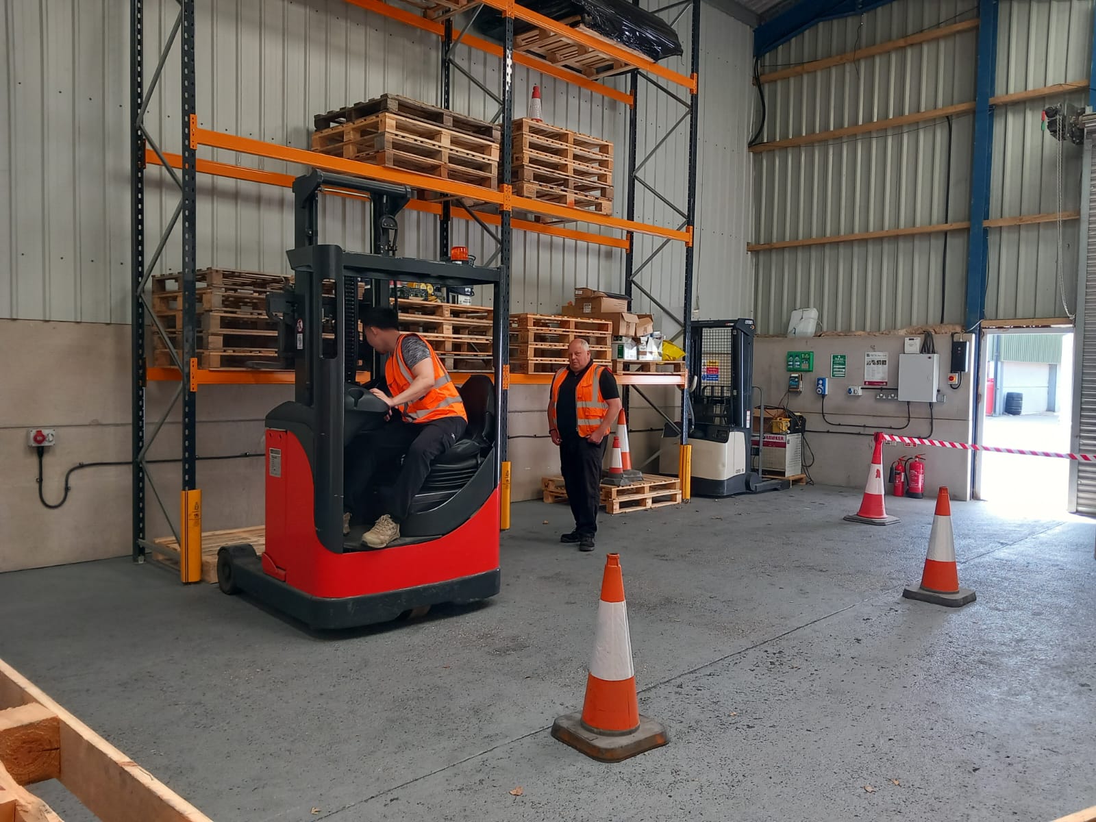 Warehouse forklift operation training with safety cones.