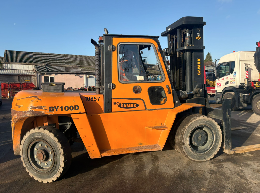 Orange forklift parked in industrial yard.