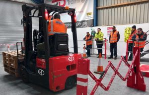 Forklift training session with safety group observing.