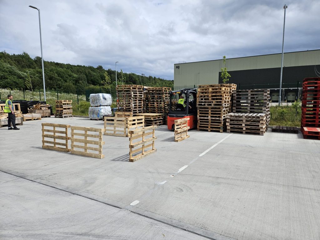 Forklift stacking wooden pallets in industrial yard